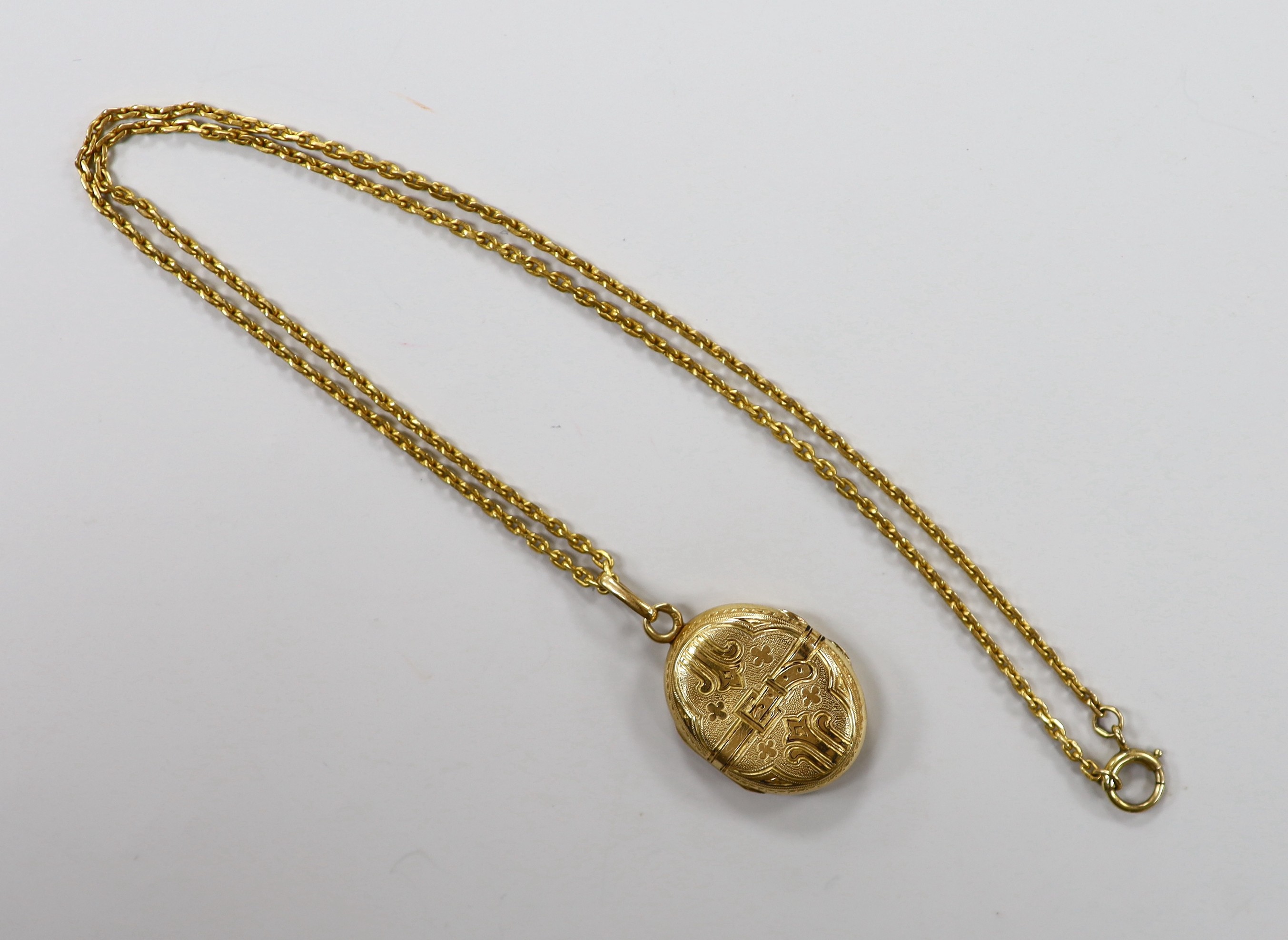 A continental engraved yellow metal oval locket, overall 38mm, on a 9ct chain, 47cm, gross weight 18.9 grams.